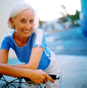 retirement Portrait of an elderly woman smiling leaning forward on bicycle handlebars